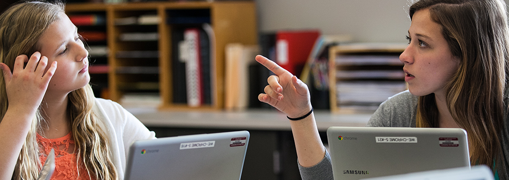 two women talking with computers.