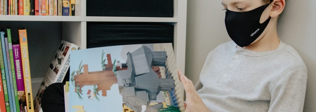 young boy reading a book in class
