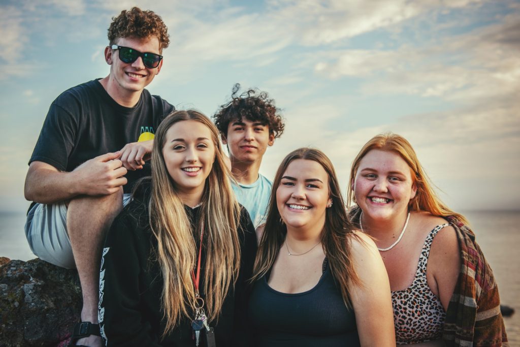 Group of friends smiling for photo with clouds in background