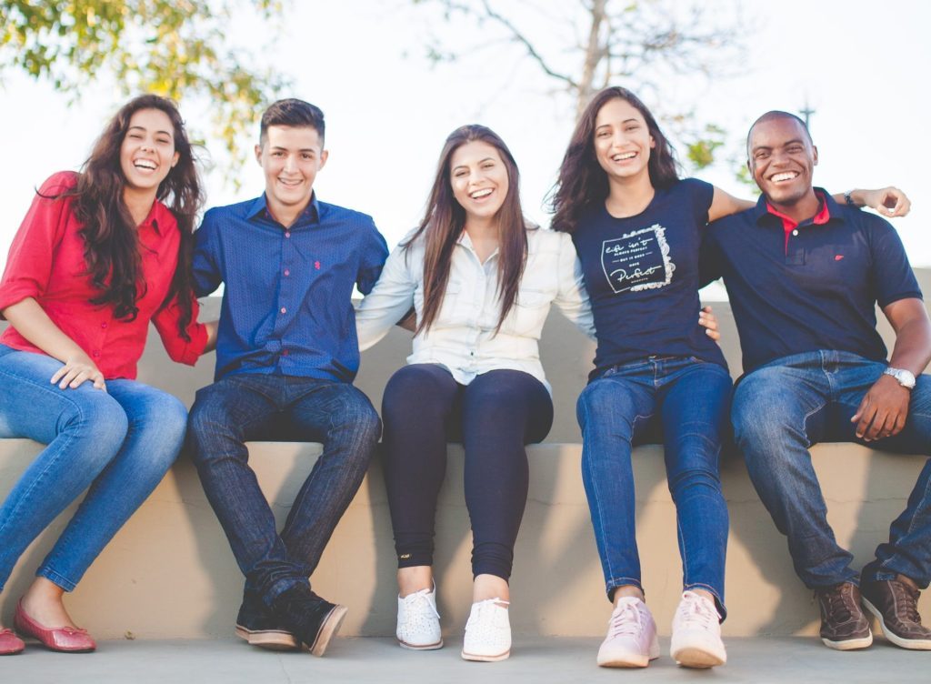 young adults, sitting on a park bench smiling