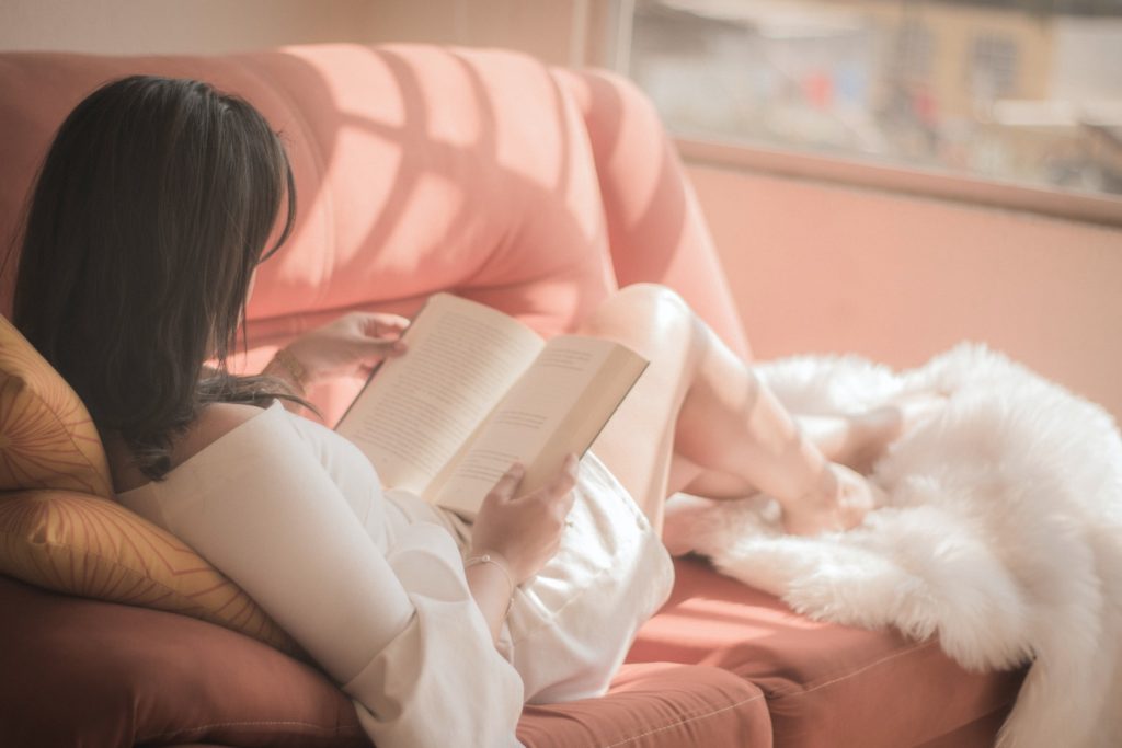 women relaxing on the sofa with a book