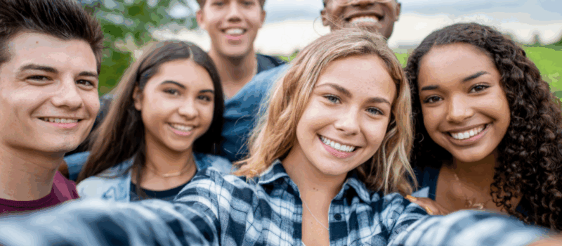 young teens are smiling taking a selfie.